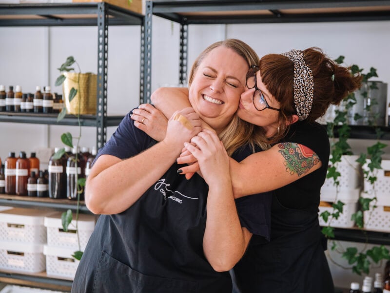 Two women joyfully hug each other with smiles on their faces